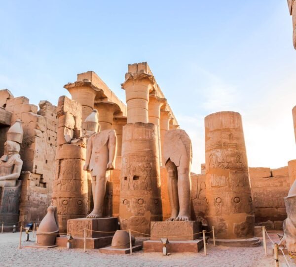 Carved sandstone columns and seated statues in a courtyard at Luxor Temple