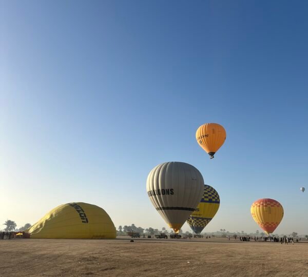 Hot air balloons taking off from a desert launch field in Luxor