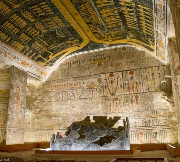 Decorated tomb walls and a vaulted painted ceiling above a fragmented stone sarcophagus in the Valley of the Kings