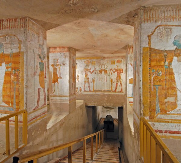 Painted Egyptian figures on square pillars beside a descending staircase in a tomb in the Valley of the Kings