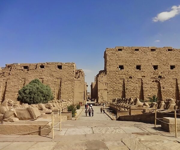Stone sphinxes lining the pathway toward the monumental entrance of Karnak Temple in Luxor