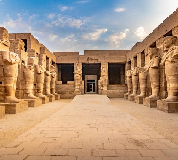 Rows of ancient standing statues lining a stone courtyard at Luxor Temple