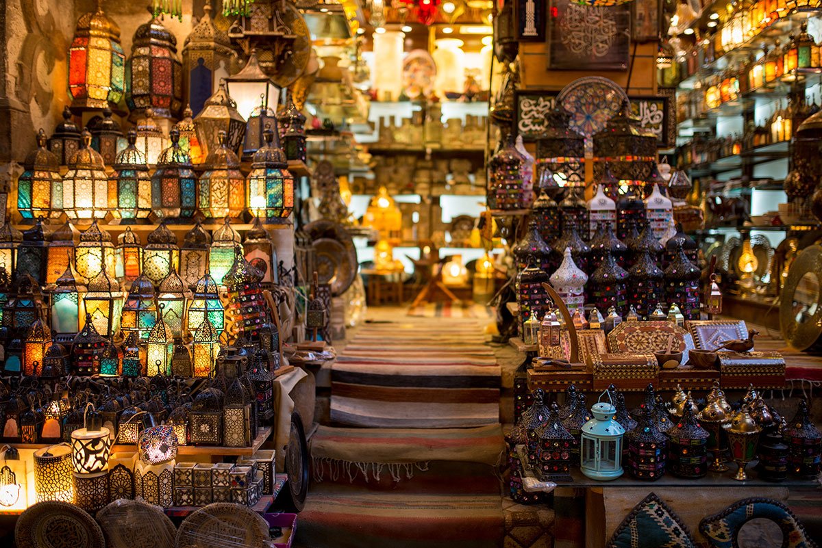Glowing colored-glass lanterns, decorative bottles and handicrafts displayed around the entrance of a market shop