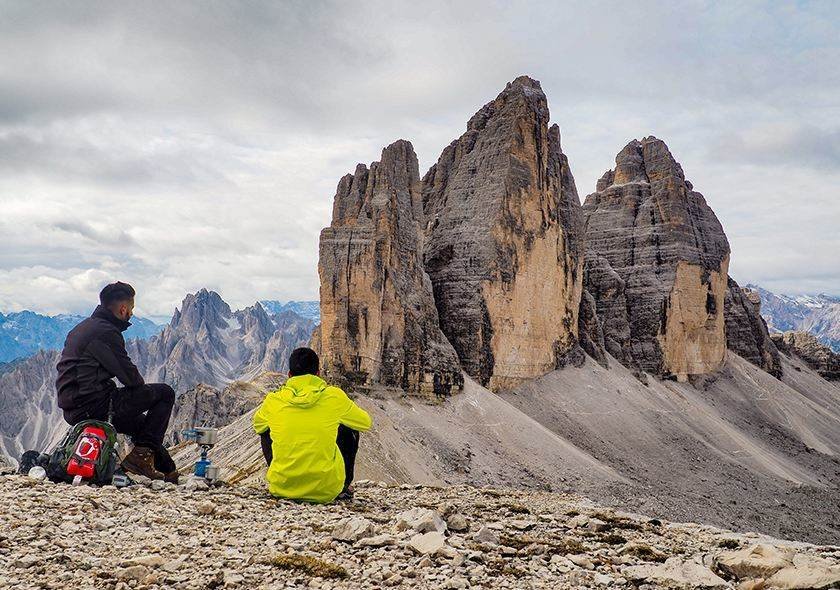 Hikers resting before jagged mountain peaks