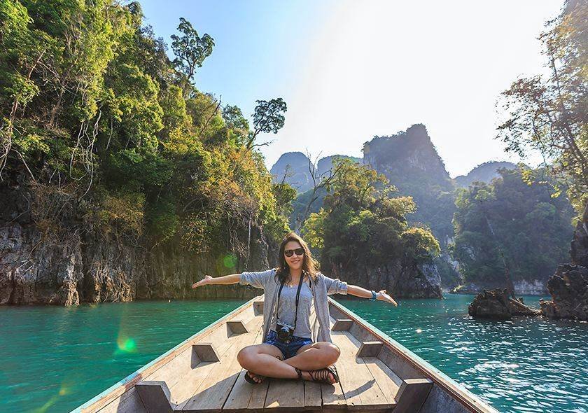 Traveler on a wooden boat among forested cliffs