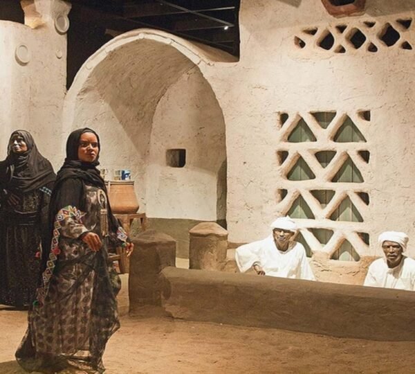 Nubian Museum exhibit with figures in traditional clothing beside the patterned walls and doorway of a home