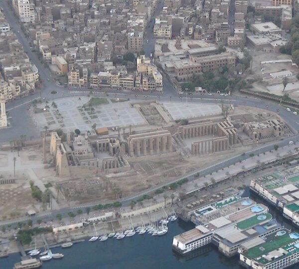 Luxor Temple beside the riverside road, with cruise boats and feluccas moored along the Nile