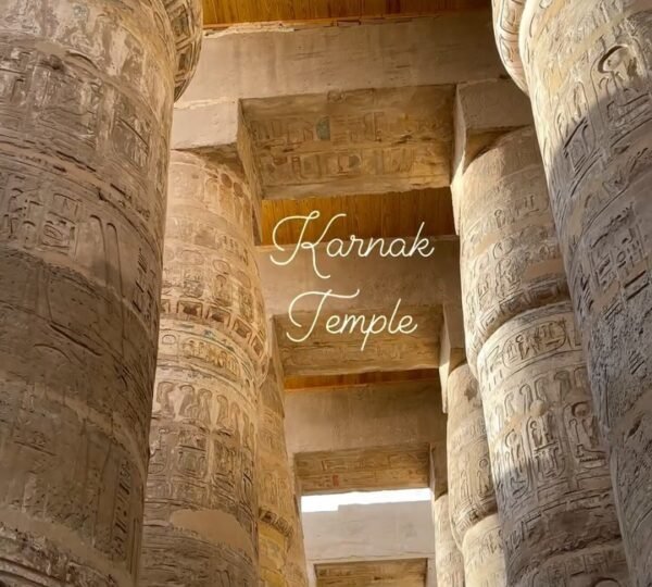 Tall hieroglyph-covered columns and stone roof beams in a vertical view of Karnak Temple’s hypostyle hall