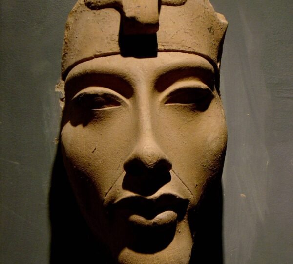 Close-up of an ancient Egyptian stone face wearing a royal headband, displayed in a museum