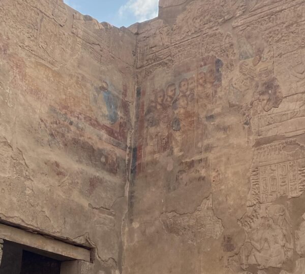 Carved hieroglyphs and traces of red and blue paint on tall ancient Egyptian temple walls