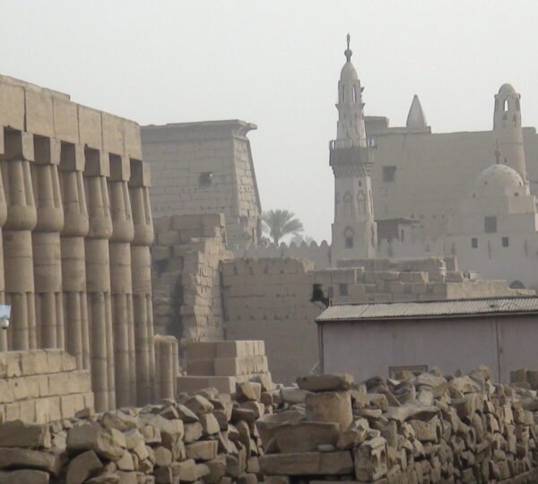 Ancient columns and stone remains at Luxor Temple with Abu Haggag Mosque and its minaret behind