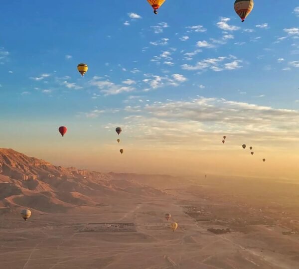 Colorful hot air balloons in a blue morning sky above Luxorโs desert plains and mountains