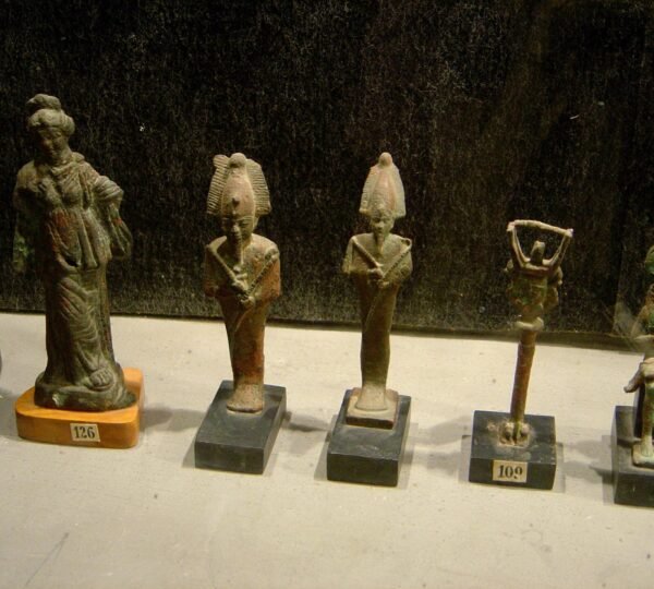Small ancient Egyptian figurines arranged on display stands inside a museum case