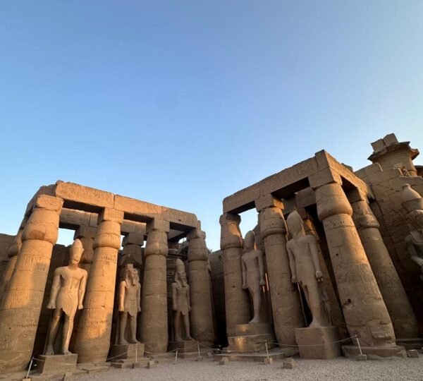 Ancient standing statues between rows of sandstone columns in a courtyard at Luxor Temple