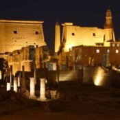 The colonnades, pylons and obelisk of Luxor Temple illuminated beneath Abu Haggag Mosque’s minaret at night