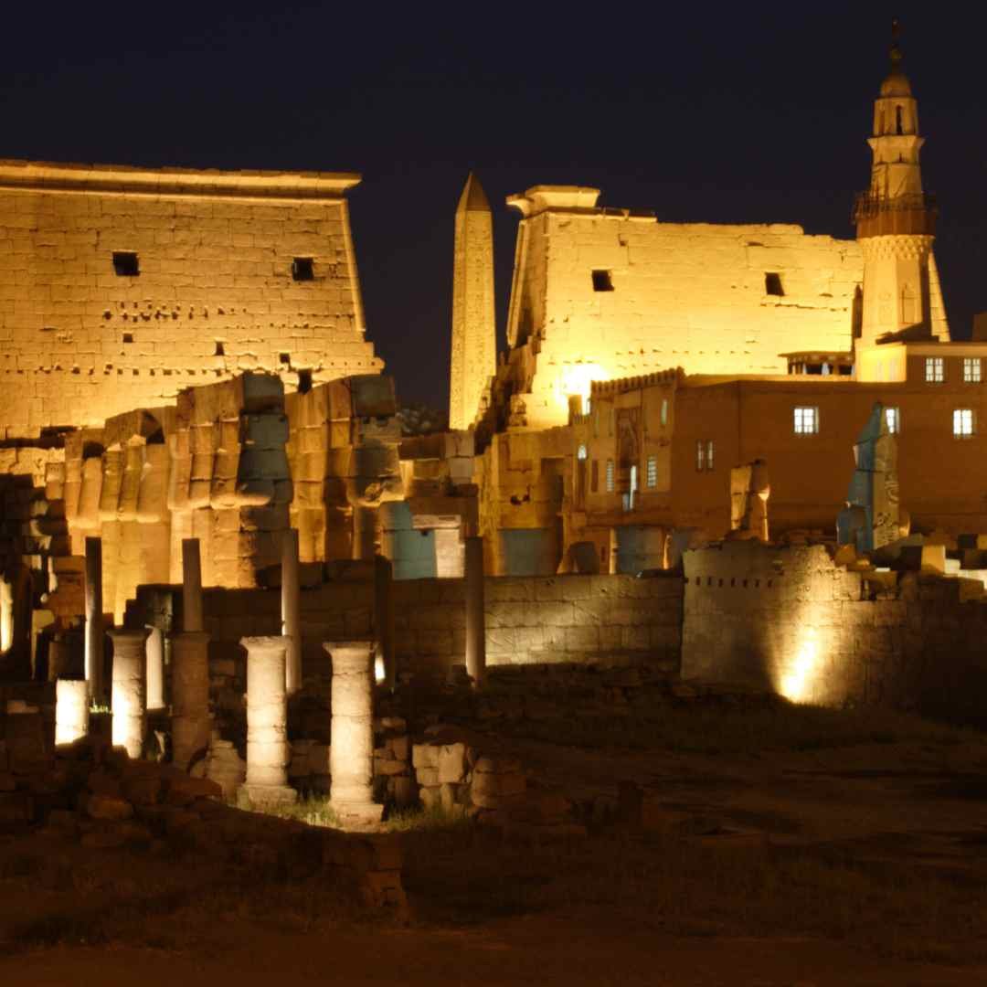 The colonnades, pylons and obelisk of Luxor Temple illuminated beneath Abu Haggag Mosque’s minaret at night