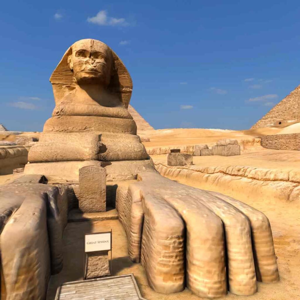 The Great Sphinx of Giza seen from the front, with its long stone paws and a pyramid behind
