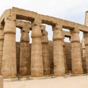 Rows of carved sandstone columns with closed papyrus-shaped capitals and stone lintels at Luxor Temple